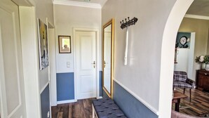 Ein Flur mit einer Bank, einem Spiegel und einer Uhr an der Wand.