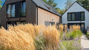 Een modern huis met twee verdiepingen, een schuin dak, grote ramen en een duidelijke schoorsteen.