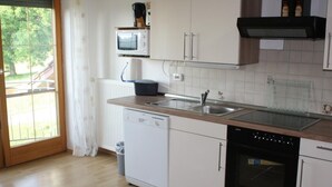 Eine Küche mit Geschirrspüler, Backofen, Mikrowelle und Spüle.