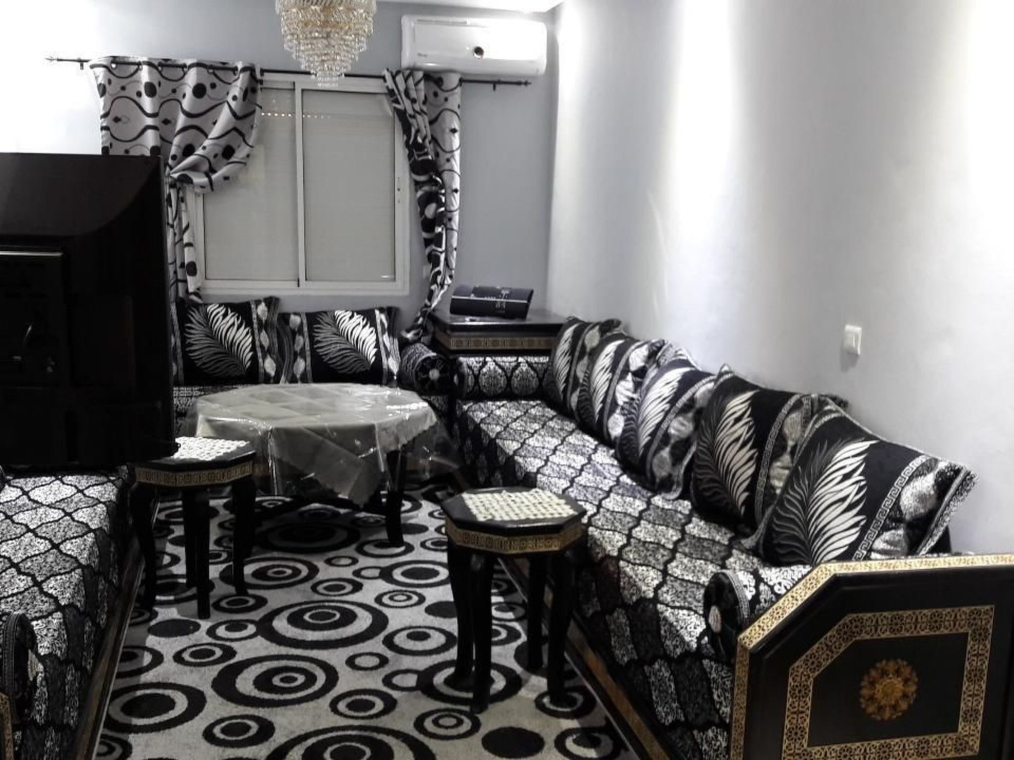 A room with a black and white patterned sofa, a round table, and two small side tables.
