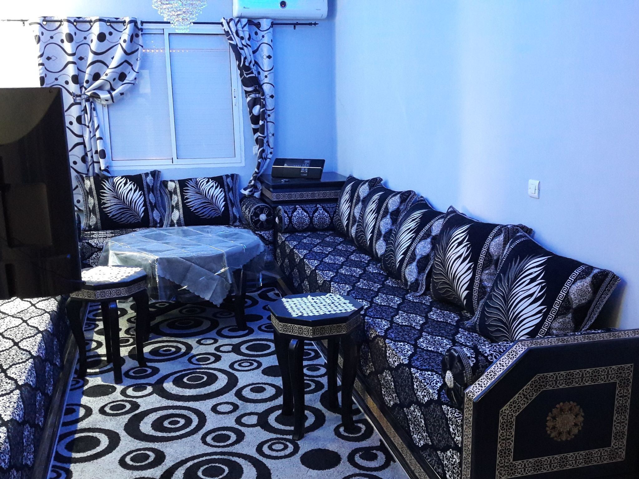 A room with a patterned floor, a sofa, a small table, and a television.