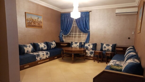 A living room with a sectional sofa, a round coffee table, and a dining table. - Résidence Annaser 1 by Interhome (Agadir)