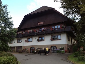 Il s’agit d’un bâtiment de style alpin traditionnel, doté d’une façade en bois, de nombreux balcons ornés de jardinières et d’une enseigne indiquant qu’il s’agit d’un restaurant.