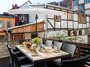 Un área de comedor al aire libre con una mesa lista para dos personas, rodeada de sillas de mimbre.