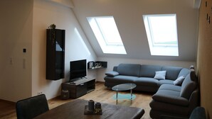 A modern loft apartment with a large gray sectional sofa, a small round coffee table, a flat-screen TV, and skylights. - Appartement mit Balkon by Interhome (Lasel)
