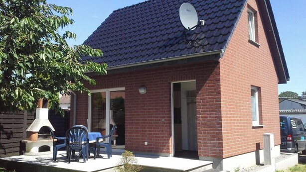 A brick house with a satellite dish, a chimney, and a patio with outdoor furniture. - Kleines Ferienhaus mit Garten in Wismar by Interhome (Wismar)