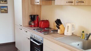 A compact kitchen with wooden cabinets, a built-in oven, a coffee maker, and a toaster. - Kleines Ferienhaus mit Garten in Wismar by Interhome (Wismar)