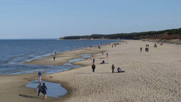 Une vaste plage de sable où l’on peut voir des gens se promener et se détendre.