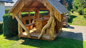 A wooden gazebo with a sloped roof, a table, and benches. - FH Auf dem Holzweg by Interhome (Bansin)