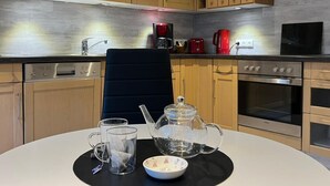 Een moderne keuken met houten kastjes, een magnetron, een koffiezetapparaat en een waterkoker op het aanrecht.