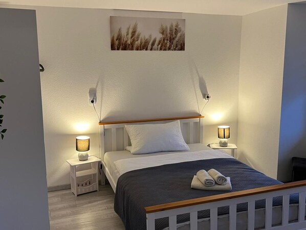 A bedroom with a bed, bedside lamps, a wall-mounted picture, and a small bedside table. - Zum Rosenhügel by Interhome (Hellenthal)
