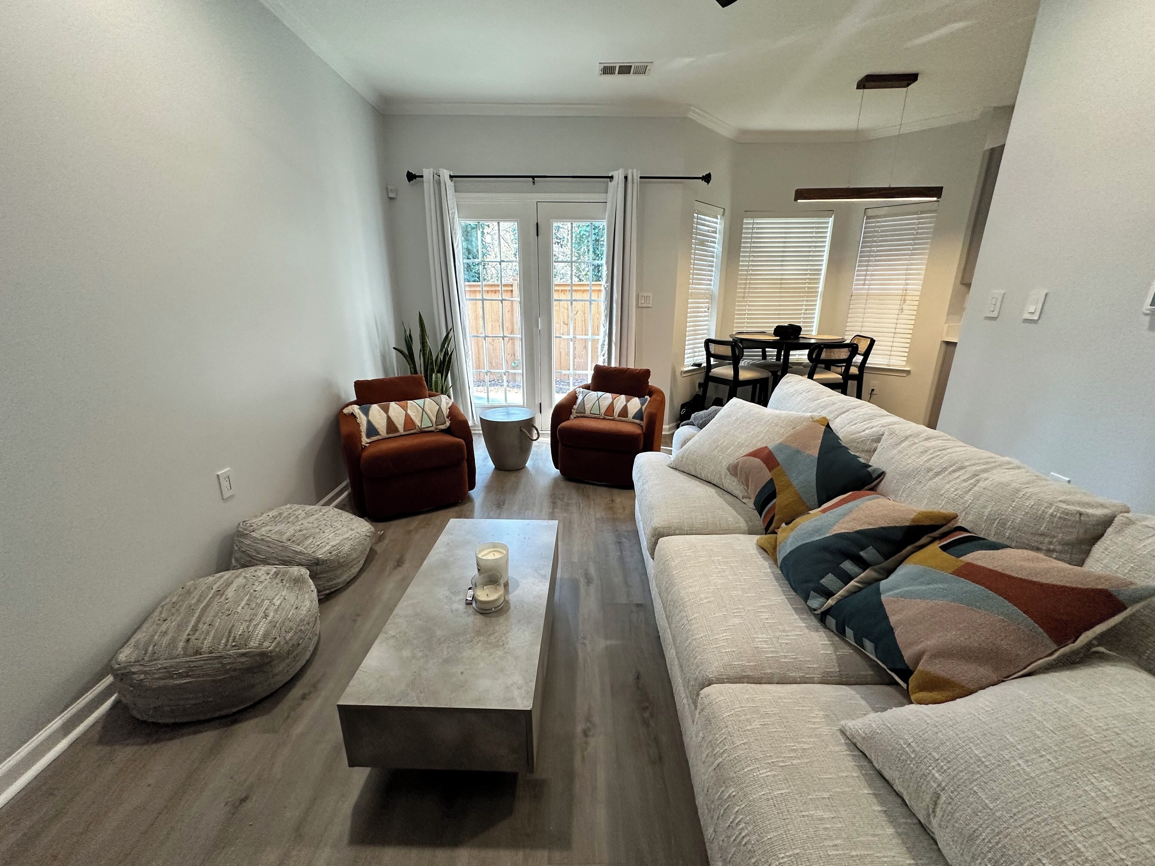 Un salon moderne comprenant un canapé, des fauteuils, une table basse et un coin repas avec une table et des chaises.