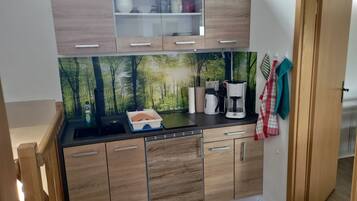 Eine kleine Küche mit Holzausstattung, einer eingebauten Mikrowelle und einer Kaffeemaschine.
