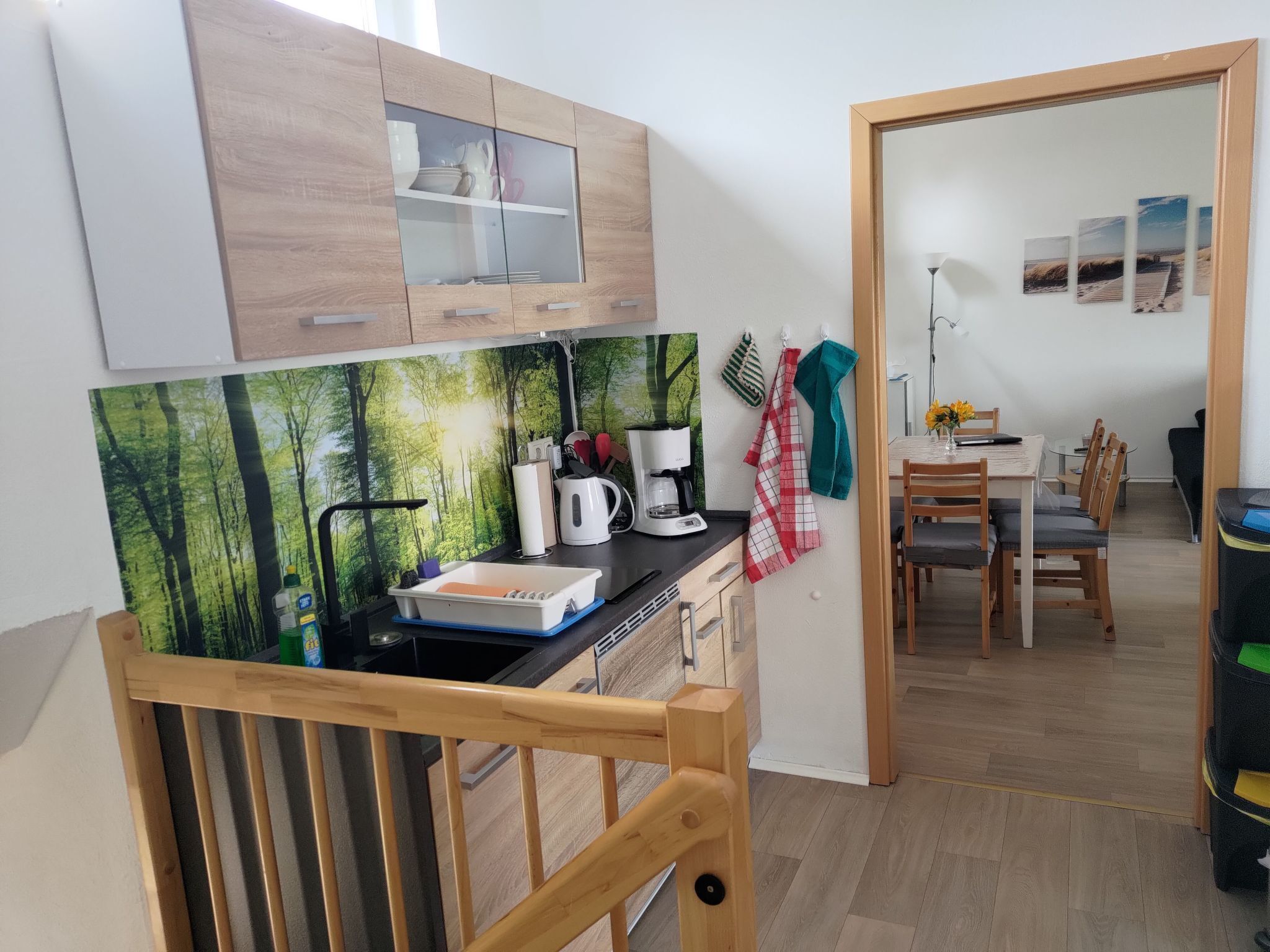 Eine kompakte Küche mit Holzausstattung, einer Kaffeemaschine und einem Essbereich mit Tisch und Stühlen.
