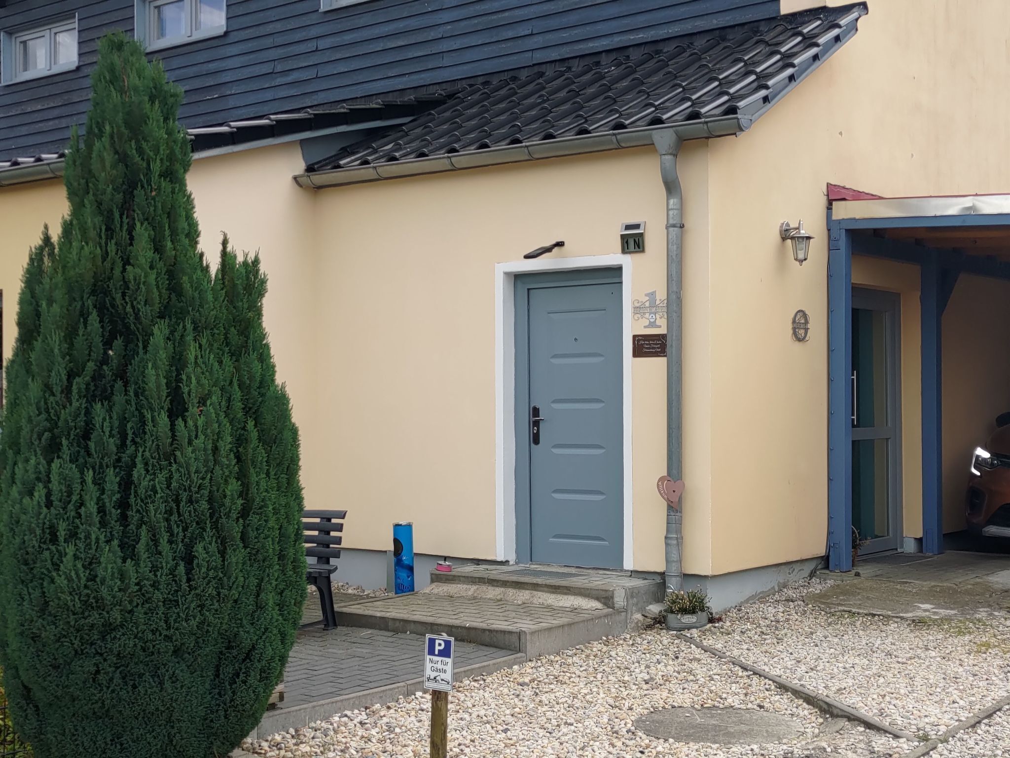 Ein Gebäude mit einer blauen Tür, einem Parkschild und einer kleinen Bank.