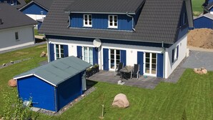 A two-story house with a dark roof, blue exterior walls, and a covered patio area. - Poseidon by Interhome (Seebad Altefähr)