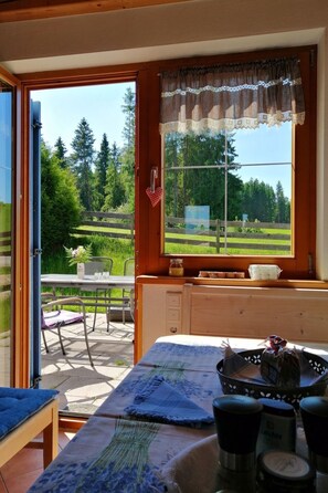 Una habitación acogedora con una mesa de madera, un banco y un ventanal con vistas a un paisaje verde.