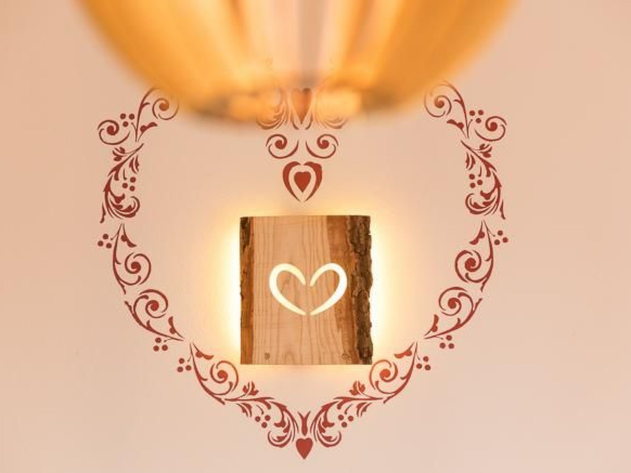 Een houten plaquette met een hartmotief, omringd door decoratieve krullen en bloemversieringen.