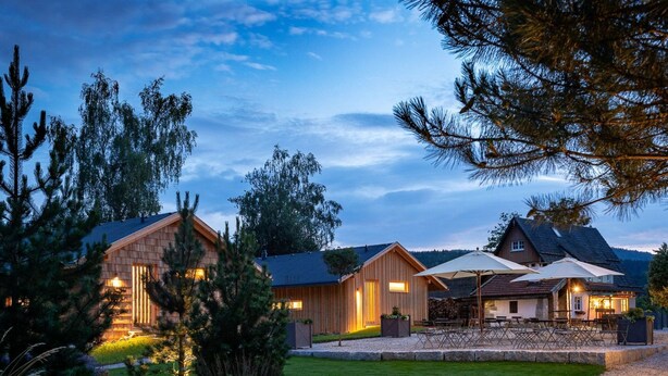 A modern lodge with multiple wooden cabins, a well-maintained lawn, and outdoor seating. - Luxuschalet im Forstgut - Raum für wertvolle Zeit by Interhome (Regen)