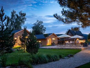 Un moderno albergue con varias cabañas de madera, un césped cuidado y mobiliario exterior.