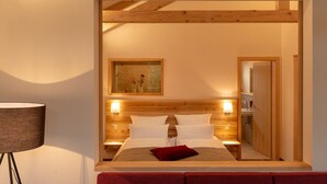 A hotel room with a wooden headboard, a large bed with white linens, two bedside lamps, a red throw pillow, and a painting above the bed. - Luxuschalet im Forstgut - Raum für wertvolle Zeit by Interhome (Regen)