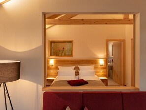 A hotel room with a wooden headboard, a large bed with white linens, two bedside lamps, a red throw pillow, and a painting above the bed. - Luxuschalet im Forstgut - Raum für wertvolle Zeit by Interhome (Regen)