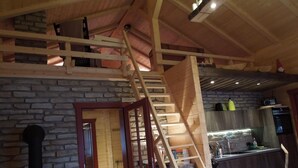 Een rustiek interieur met een houten trap, stenen muren en een keukenhoek met moderne apparatuur.
