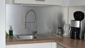 Una cocina moderna con un lavamanos de acero inoxidable, una cafetera y un hervidor.