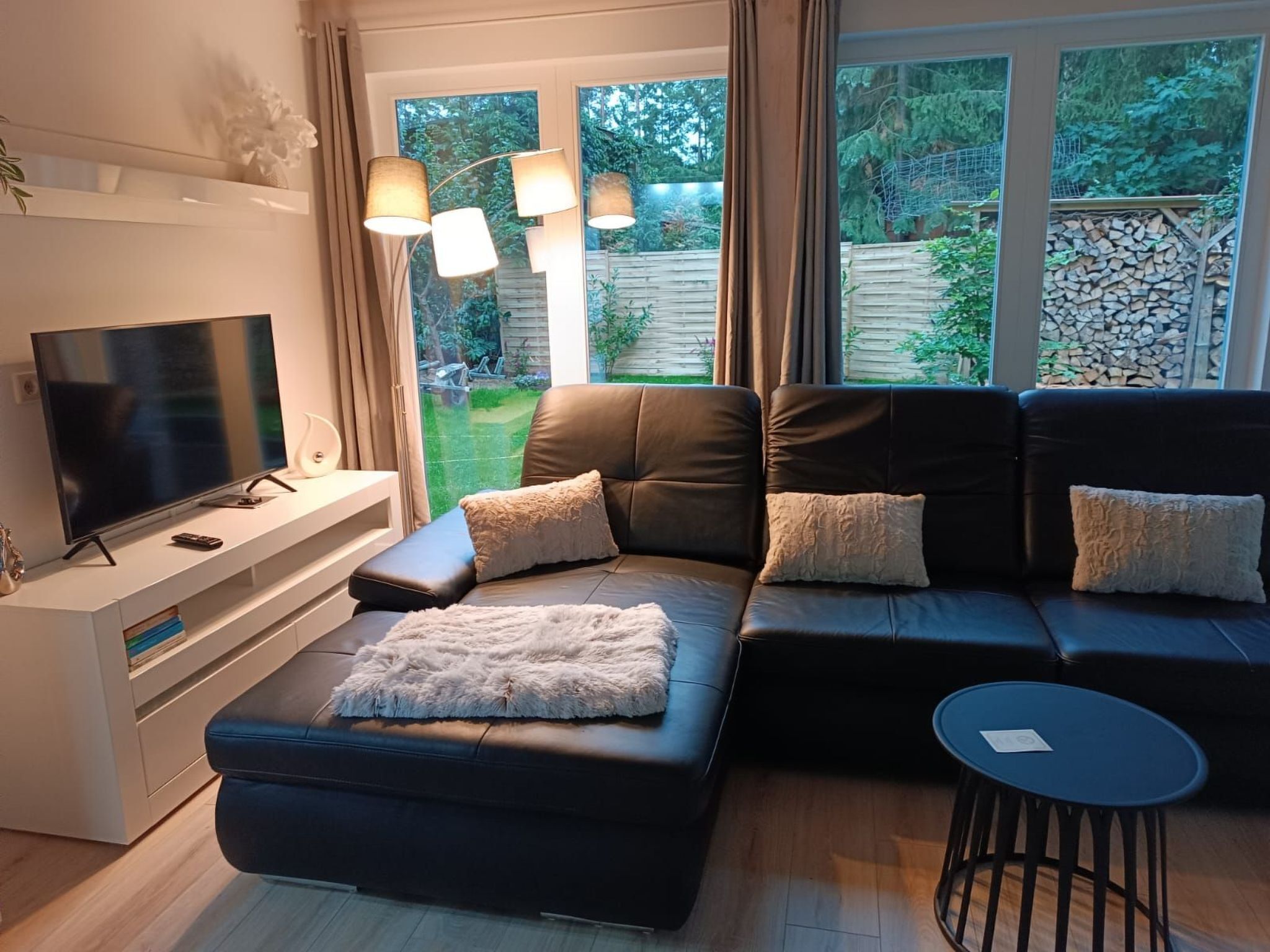 Ein modernes Wohnzimmer mit einer Eckcouch, einem Flachbildfernseher und einem kleinen runden Tisch.