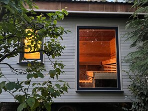 En vit byggnad med ett stort fönster som ger en inblick i det träinredda rummet.