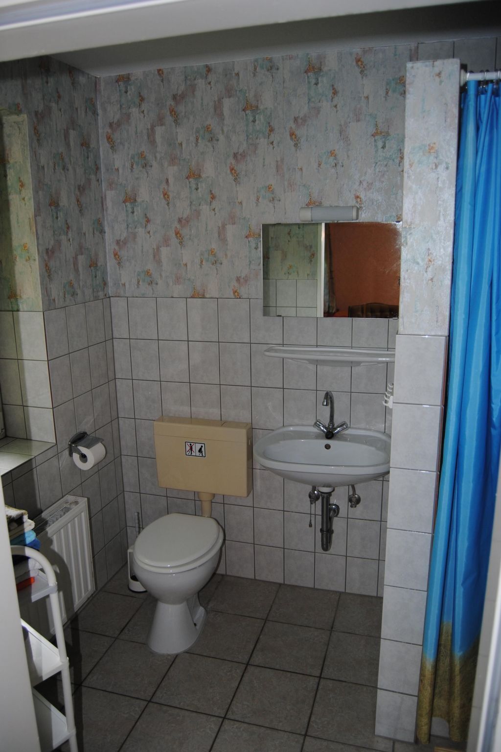 A small bathroom with a toilet, sink, and shower curtain.