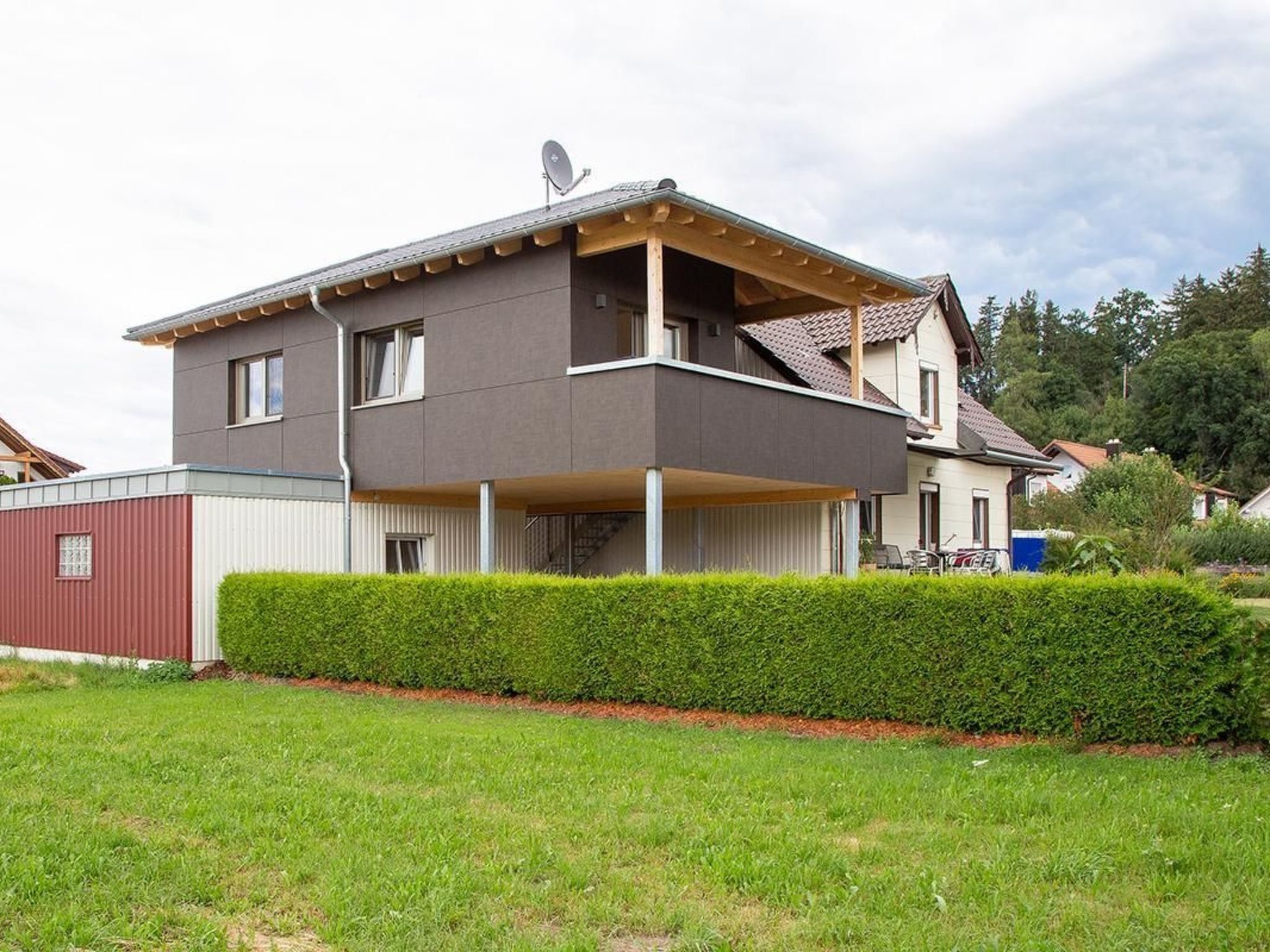 A modern two-story house with a balcony and a satellite dish.