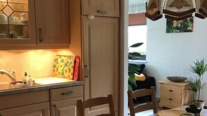 Una cocina con armarios de madera, una mesa de comedor con individuales y una lámpara colgante.