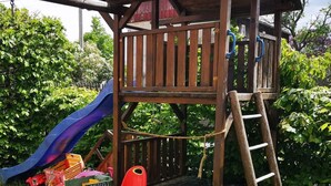 Une structure de jeu en bois, dotée d’un toboggan et d’une échelle d’escalade.