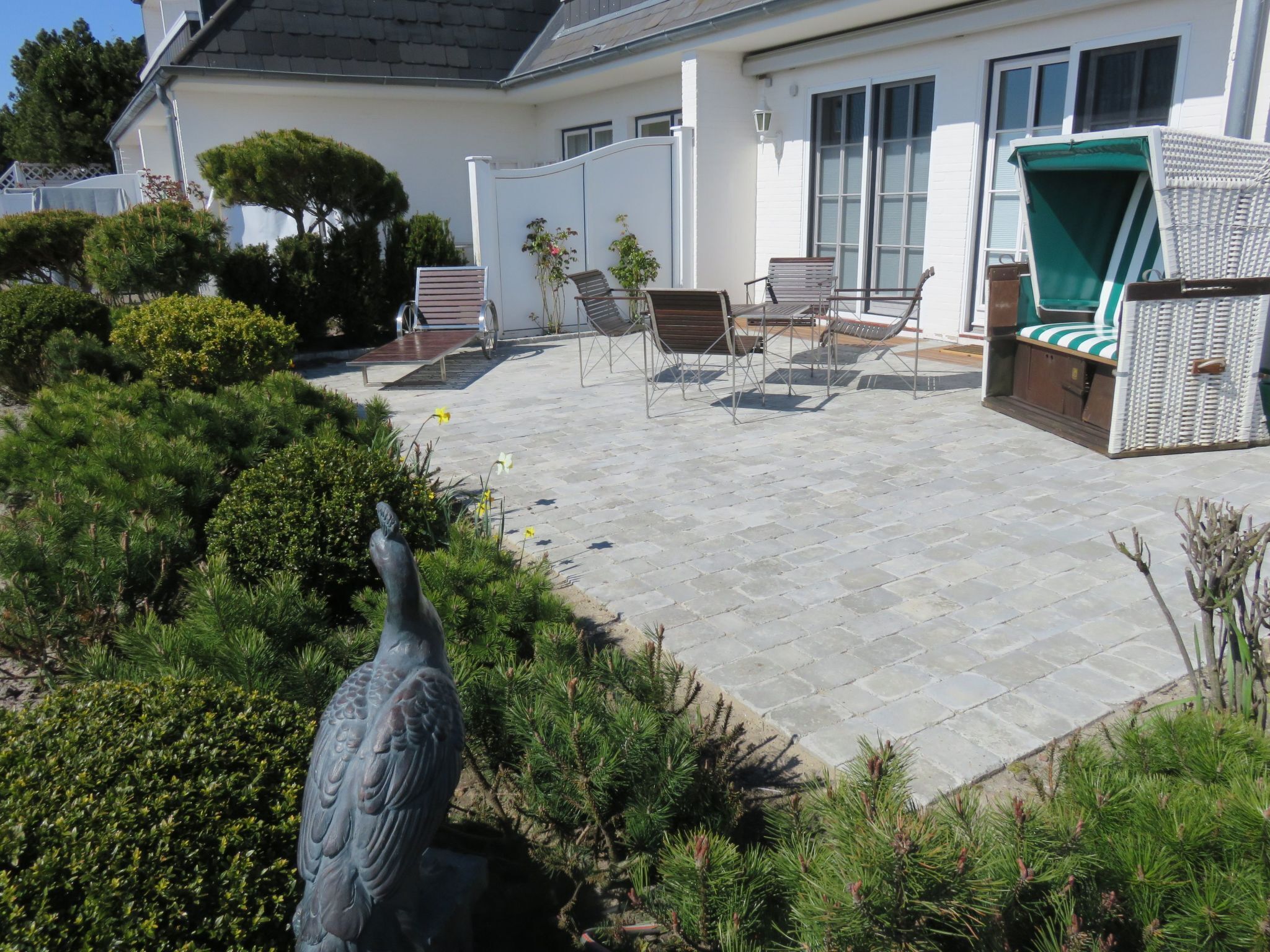 A patio with stone flooring, outdoor furniture, and a bird sculpture.