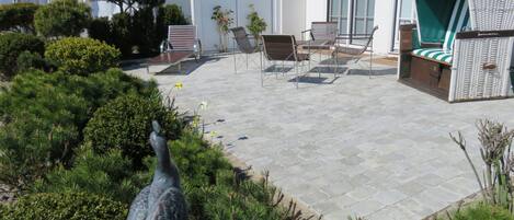 A patio with stone flooring, outdoor furniture, and a bird sculpture.