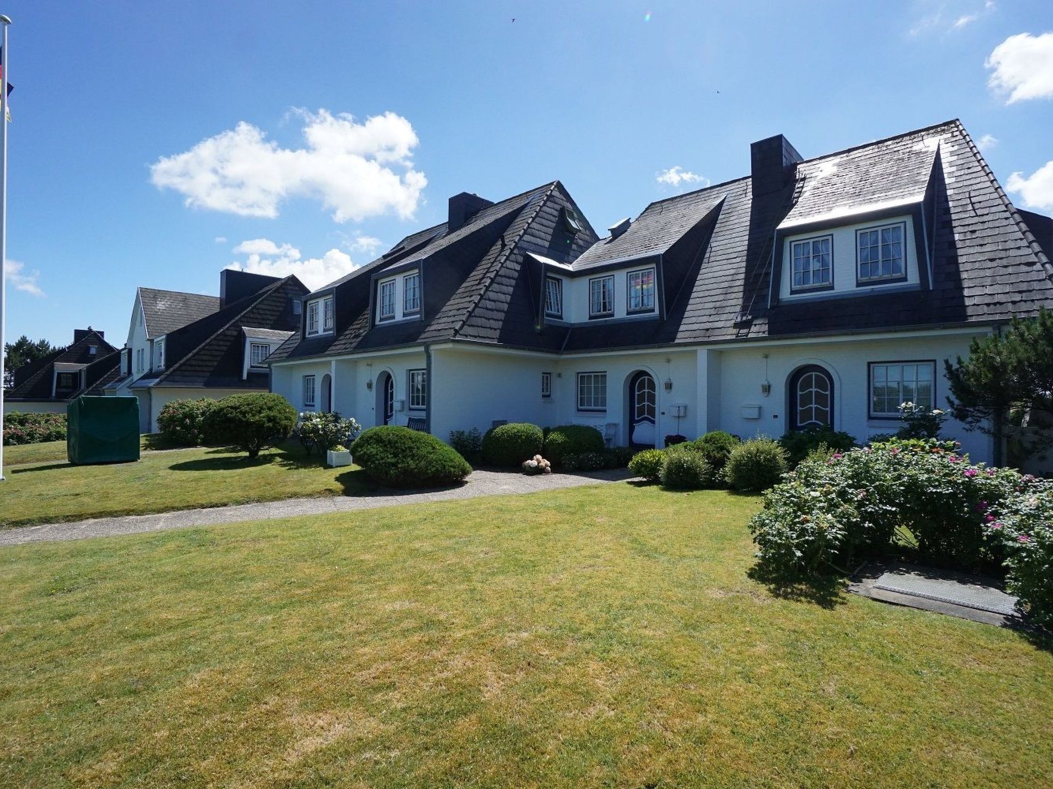 Uma casa grande de dois andares com fachada simétrica, várias janelas e um gramado bem cuidado.