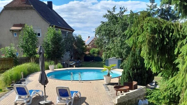 Un pati amb una piscina, gandules i un camí de maons que condueix a la piscina.