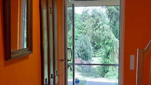 Habitació amb parets taronges, una banca de fusta, una porta que dóna a l'exterior i vista a vegetació.
