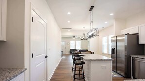 Une cuisine moderne avec des meubles blancs, des appareils en acier inoxydable et un îlot central doté de tabourets de bar.