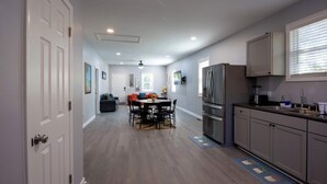 A modern kitchen with grey cabinets, a stainless steel refrigerator, and a dining area with a round table and chairs. - 4 Min to Downtown | 11 to Elon | Car Rental Avail. (Burlington)