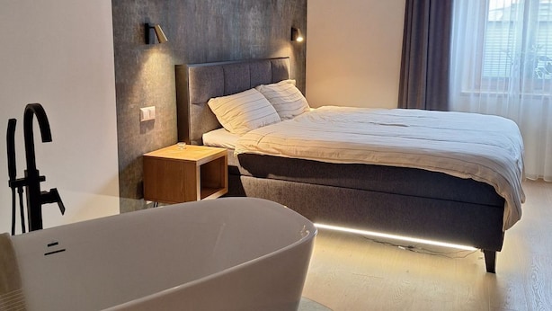 A modern bedroom with a large bed, a built-in bathtub, and a minimalist design. - Apartment Stadtmauerloft Gmünd by Interhome (Fischertratten)