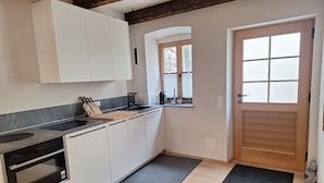 A modern kitchen with white cabinets, a black countertop, a built-in oven, and a window with blinds. - Apartment Stadtmauerloft Gmünd by Interhome (Fischertratten)