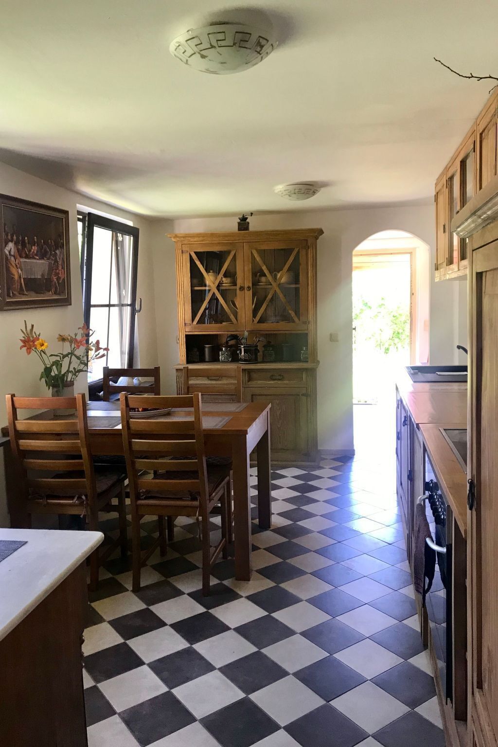 A kitchen with a checkered floor, wooden cabinets, and a dining table with chairs.