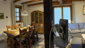 A dining area with a wooden table and chairs, a cabinet, and a television mounted on a wooden beam. - im Fachwerkstil mit Sauna und Garten by Interhome (Thomasburg)