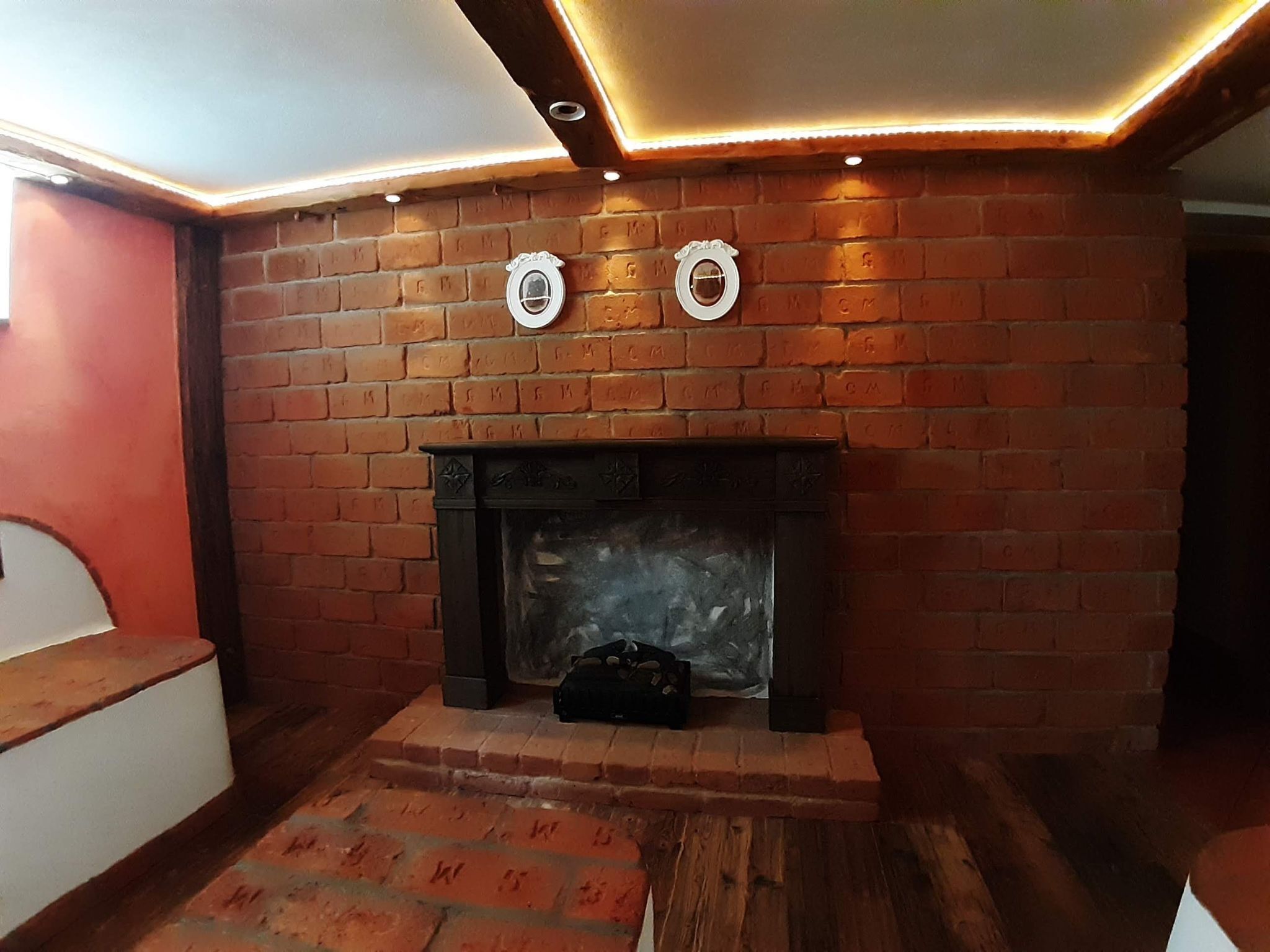Une cheminée en briques agrémentée d’éléments décoratifs et un luminaire moderne au plafond.