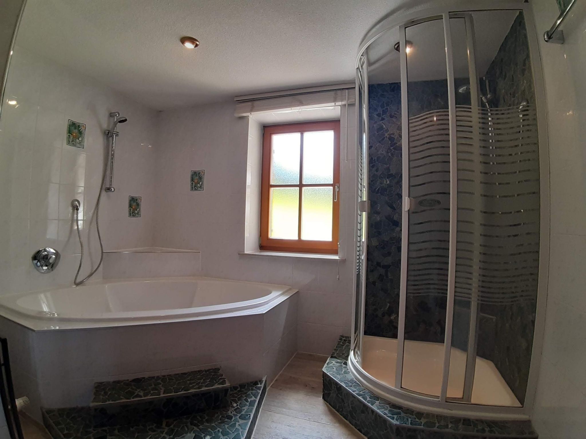 Une salle de bain avec une baignoire sur pieds, une douche à parois de verre et une petite fenêtre.
