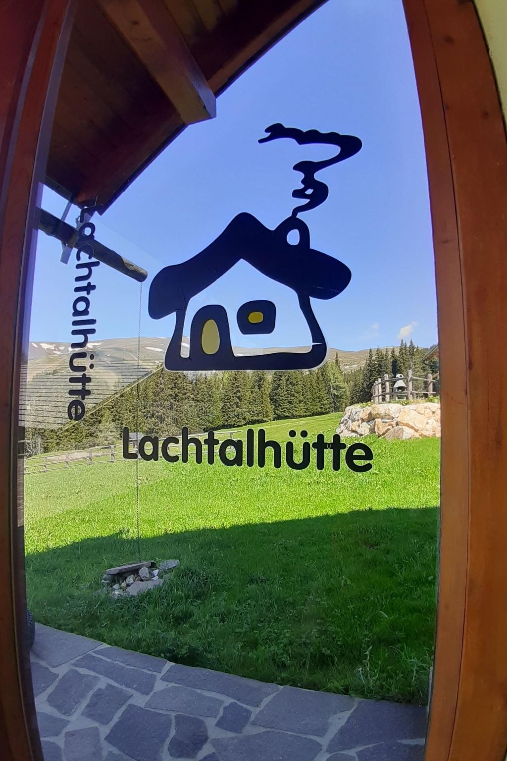 Un logo représentant une maison avec une cheminée, apposé sur une vitre, avec le texte « Lachthalhütte » en dessous.