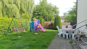 Ein Garten mit Schaukel, Spielgerüst und Essbereich mit Gartenmöbeln.