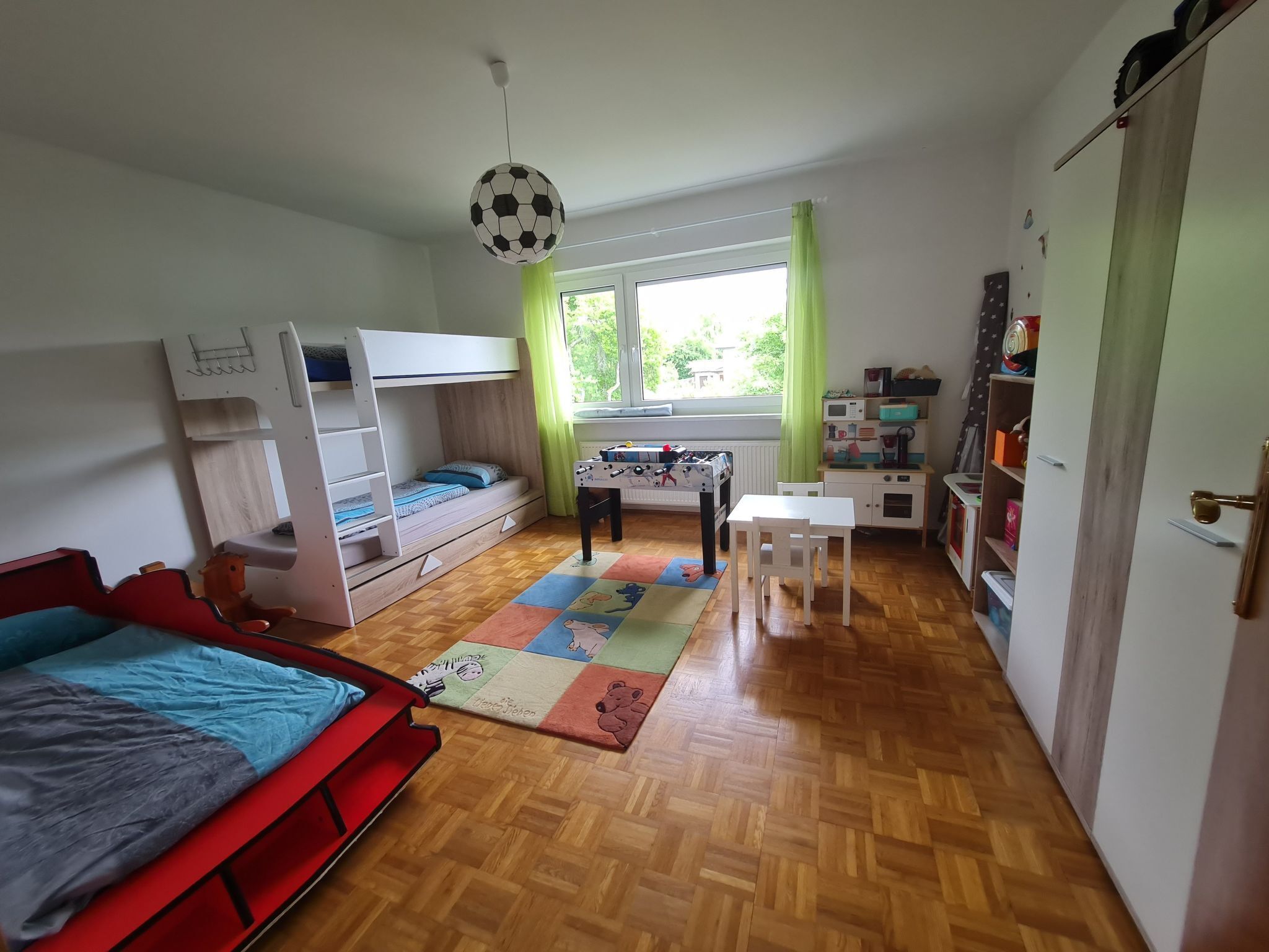 Ein Zimmer mit Etagenbett, Schreibtisch, einem kleinen Tisch und einer Schlafcouch.